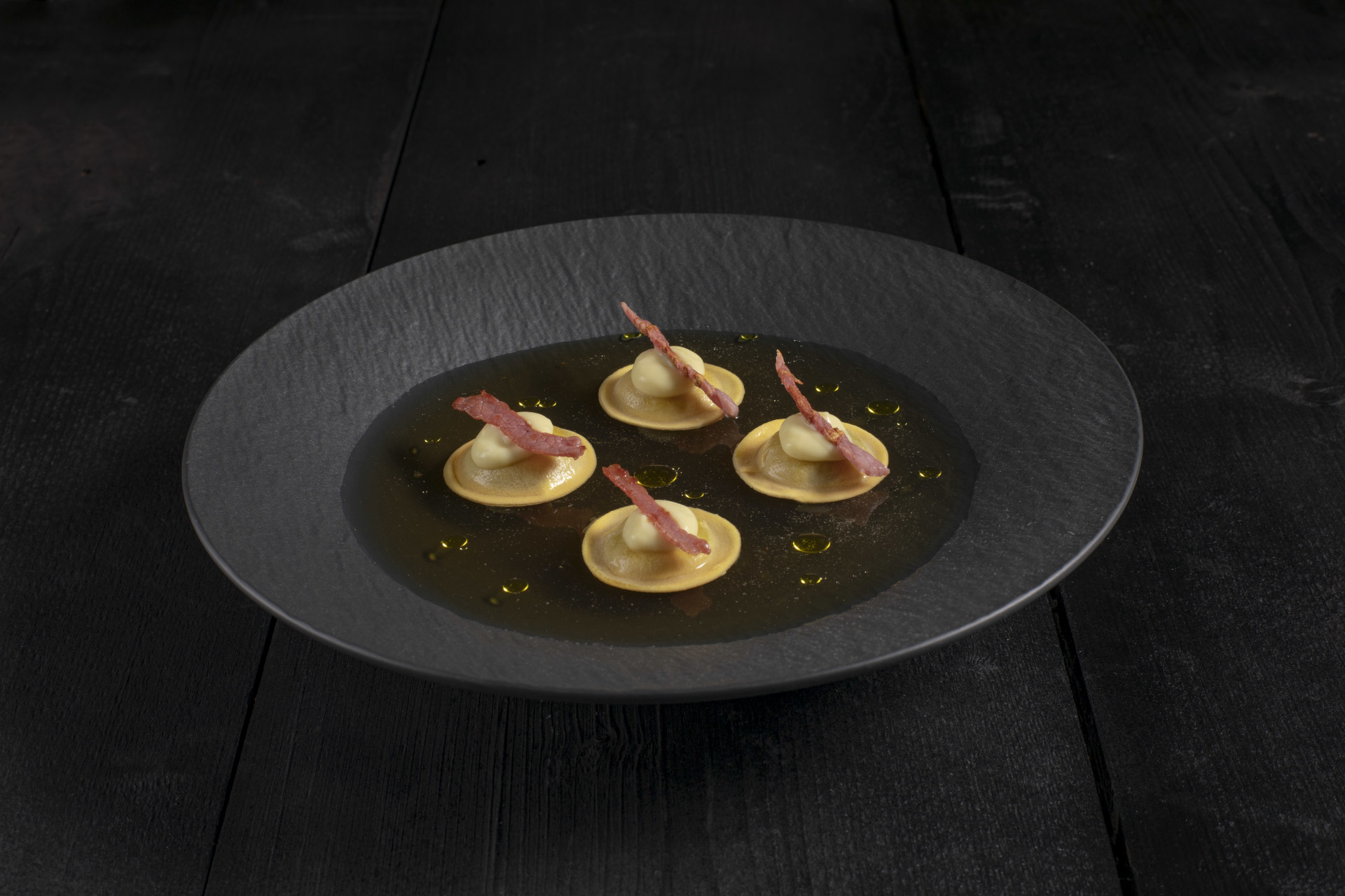 Gruyère ravioli in artichoke broth with toasted speck.
